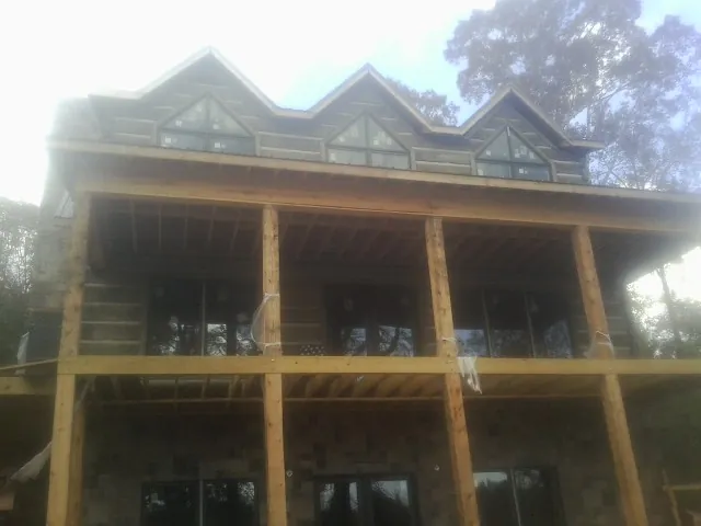 Dormers and porch framing on a large log home under construction — Roof Coating work by our crew in Upton