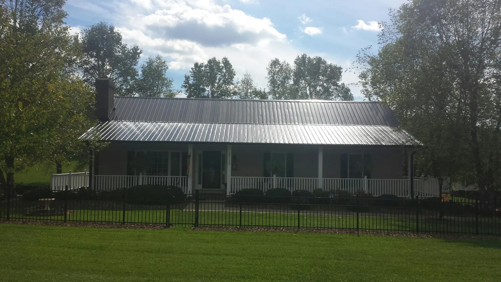 Gray metal roof on a brick ranch with a full width front porch — Gutter Guard Installation work by our crew in Upton
