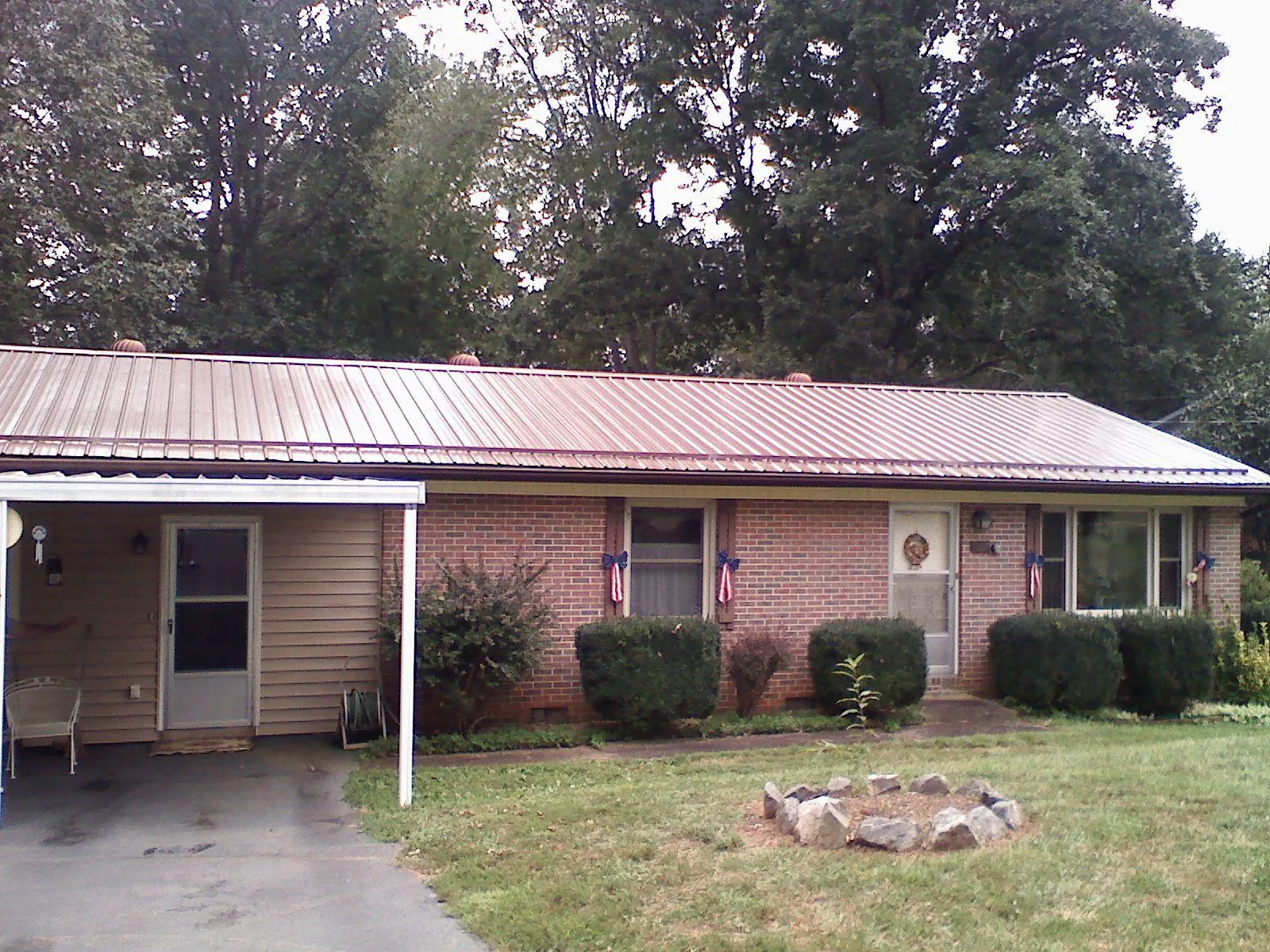 Bronze metal roof and carport on a brick ranch home — Roof Repair work by our crew in Upton